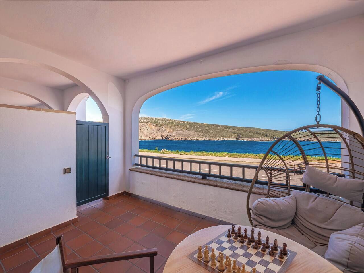 Una habitación con vista al mar, un sillón colgante y un tablero de ajedrez.