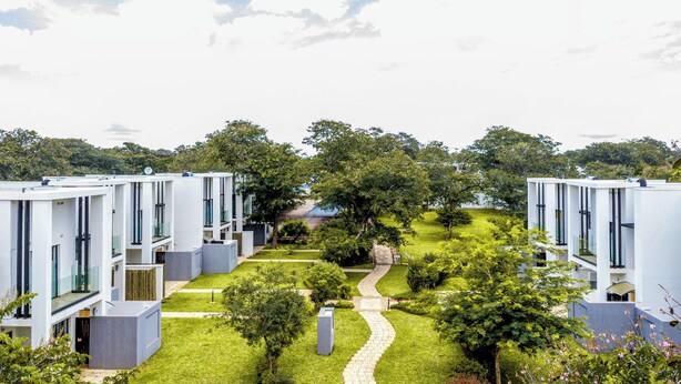 Un ensemble immobilier moderne composé de plusieurs bâtiments blancs, d’un chemin central et d’un espace verdoyant environnant.