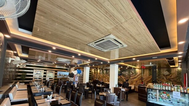 Um restaurante com várias mesas e cabines, um balcão com vitrine e um mural na parede.