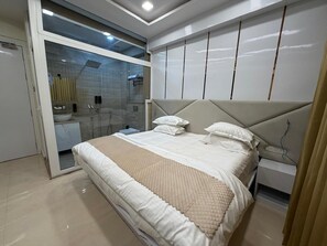 Een slaapkamer met een bed, een glazen douchecabine, een nachtkastje en een kledingkast.