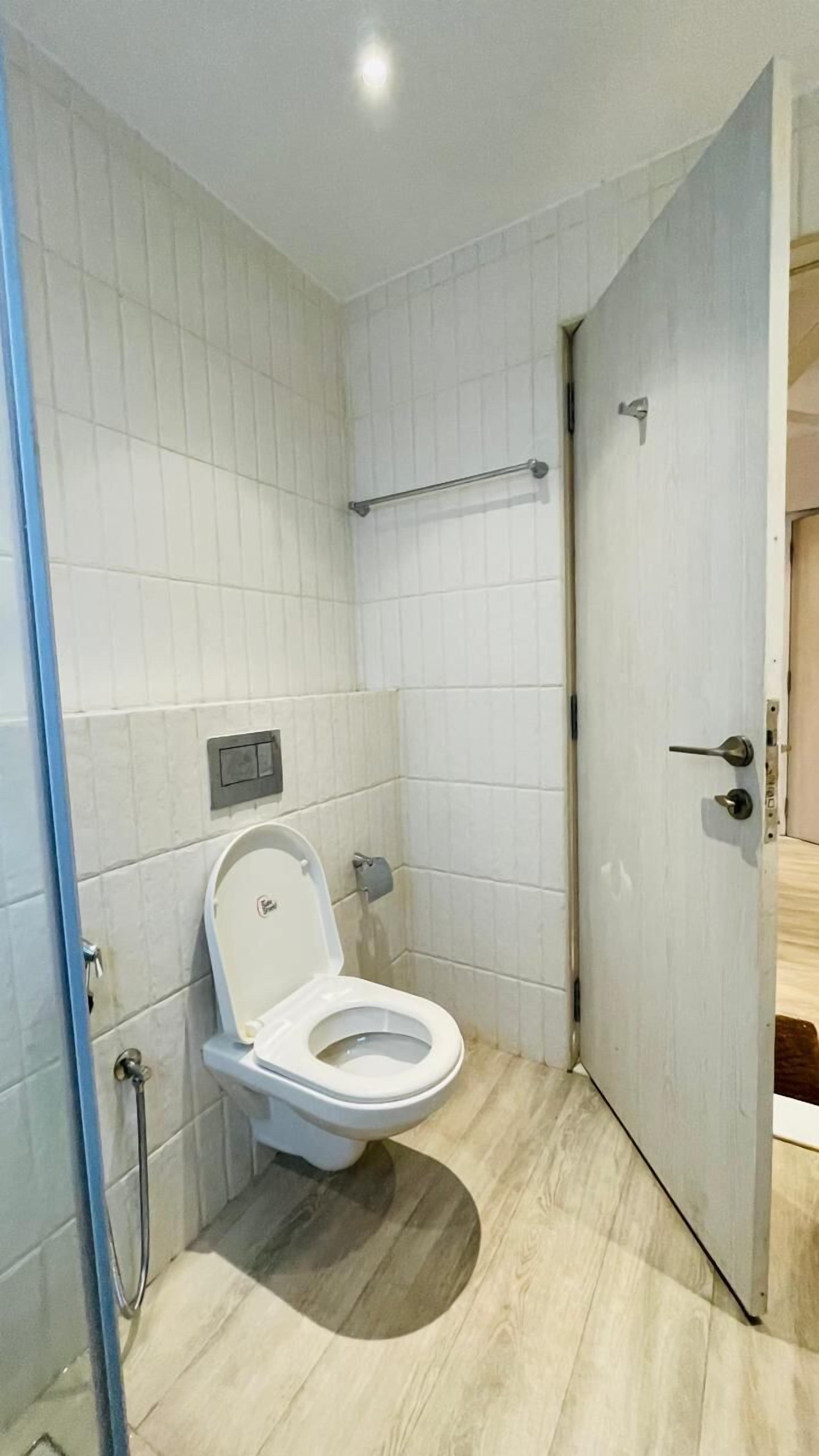 Une petite salle de bain moderne, équipée de toilettes, d’une douche et d’une porte.