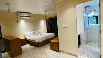A modern hotel room with a bed, bedside tables, an air conditioning unit, and a view of the bathroom.