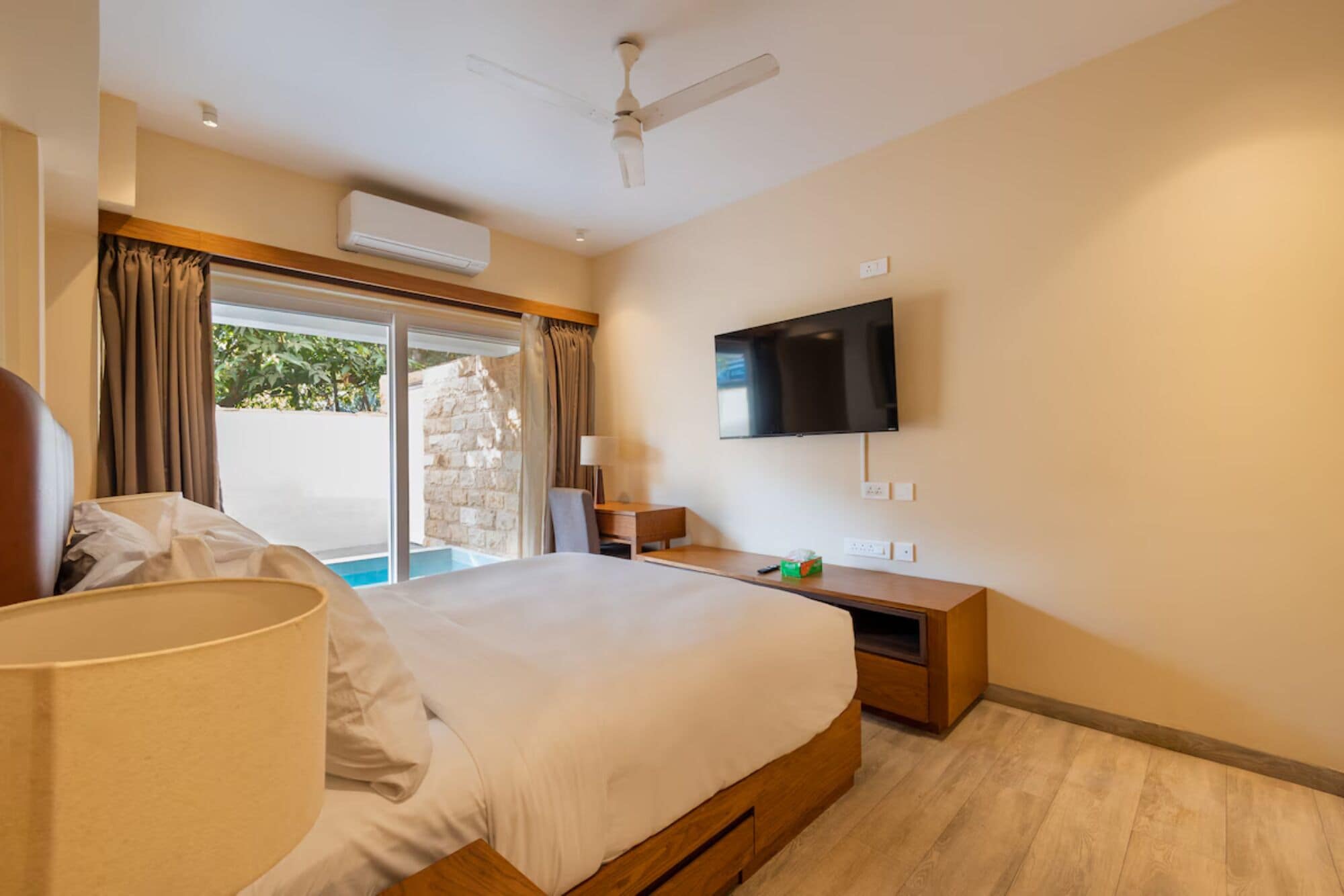 Una habitación de hotel con una cama, televisión, escritorio y ventana con cortinas.
