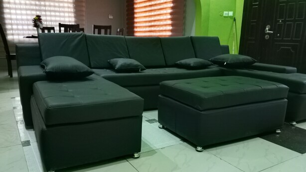A modern living room with a sectional sofa, ottomans, and a dining area with a table and chairs. - Gorgeous 3-bedroom house in Kokrobite near the beach (GJ49+MR5 Kokrobite)
