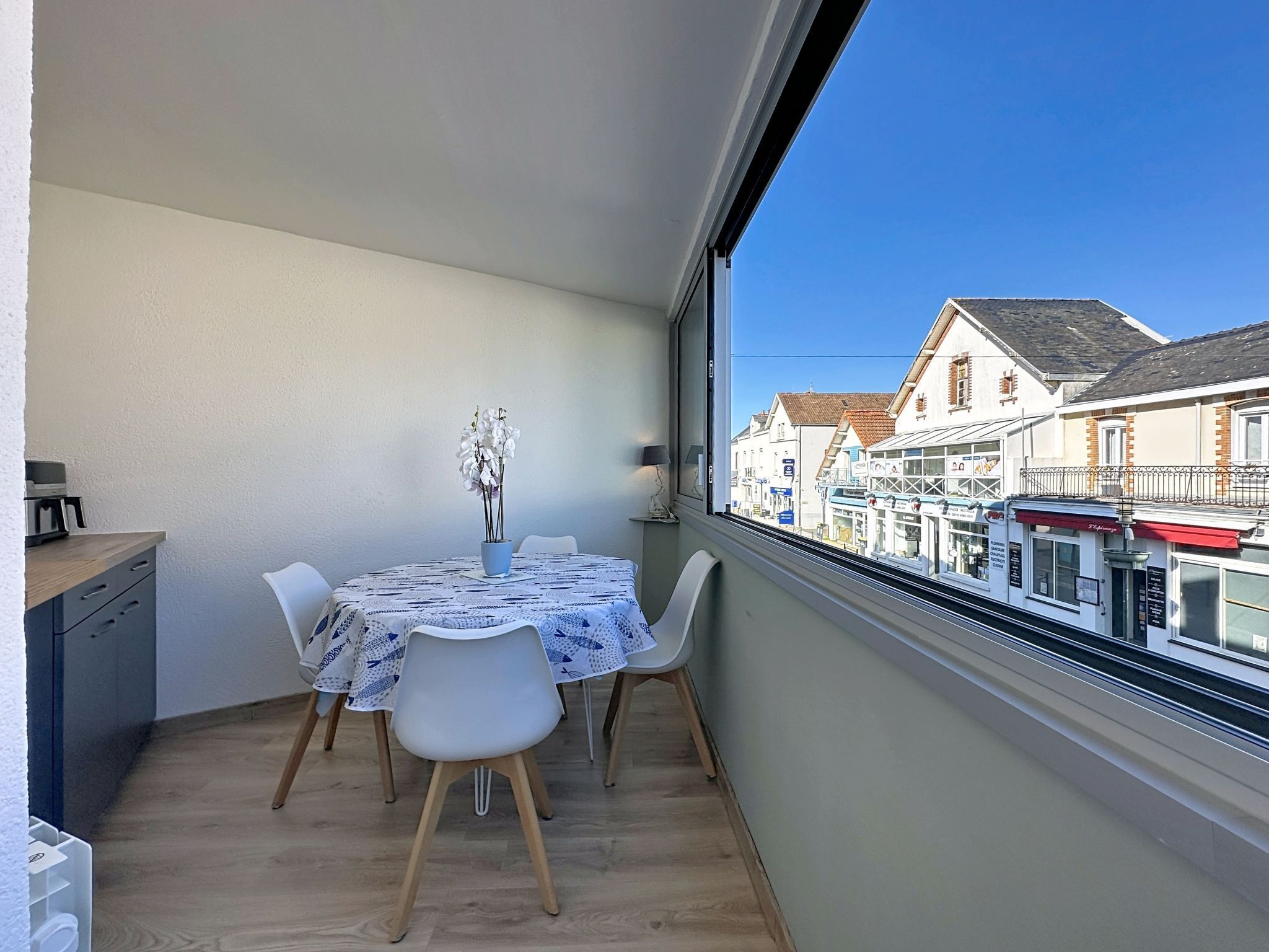 Un balcone con tavolo, sedie e un vaso di fiori.