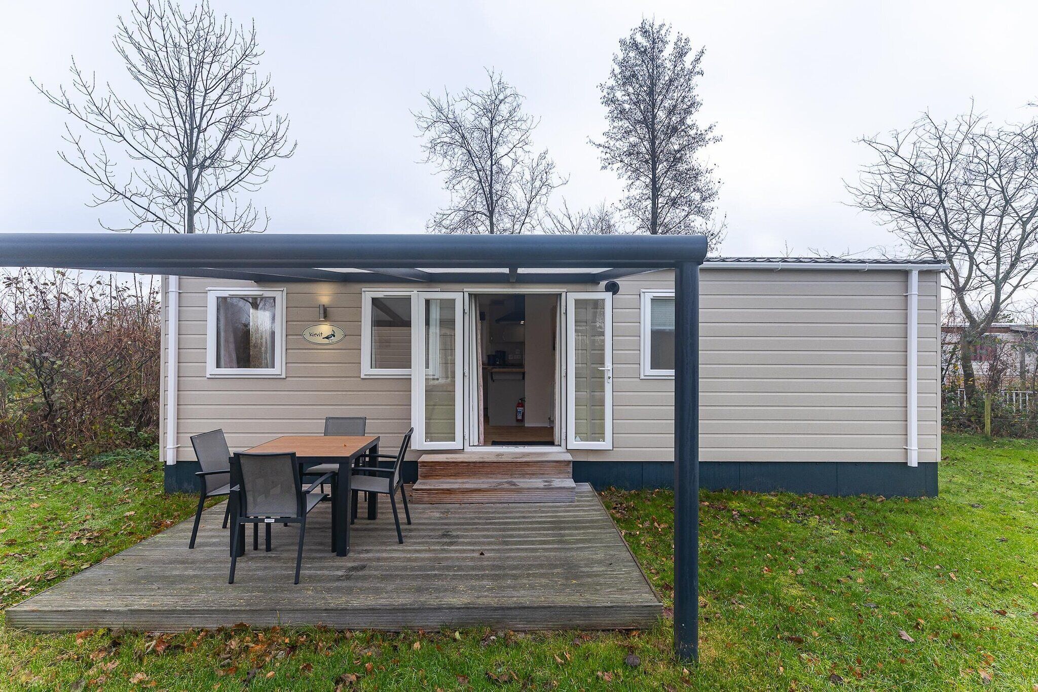 A mobile home with a deck, a table with chairs, and a covered patio area.