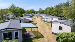 A row of mobile homes with attached porches and a grassy yard.