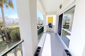 Ein Balkon mit Blick auf eine Wohngegend, einem kleinen Tisch und einem Stuhl.