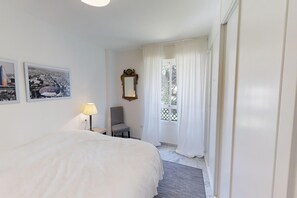 A hotel room with a large bed, a chair, a desk, a lamp, and two framed pictures on the wall. - Modern Sea-Side Apartment for 6 (San Pedro de Alcántara)