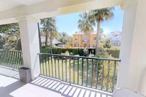 A balcony with a view of a residential area, including a yellow building and palm trees. - Modern Sea-Side Apartment for 6 (San Pedro de Alcántara)