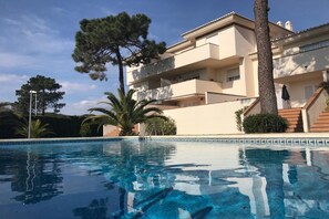 A residential building with a swimming pool, a staircase, and a large tree. - Cozy Elviria Beachside Apartment (Marbella)