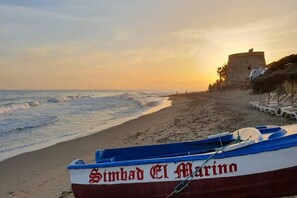 A beach with a row of sun loungers and a boat named 'Simbad El Marina' anchored near the shore. - Cozy Elviria Beachside Apartment (Marbella)