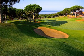 A golf course with a sand bunker, trees, and a clear sky. - Cozy Elviria Beachside Apartment (Marbella)