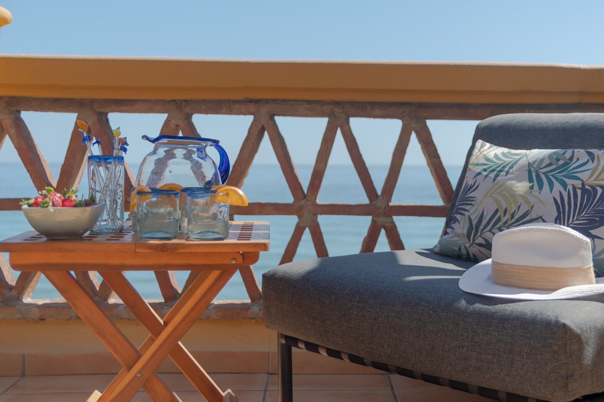 A balcony with a wooden table, a chair, and a view of the sea.