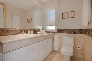 A bathroom with a marble countertop, a white sink, a toilet, and a mirror. - Elegant Seafront Retreat in Rio Real Playa (Marbella)