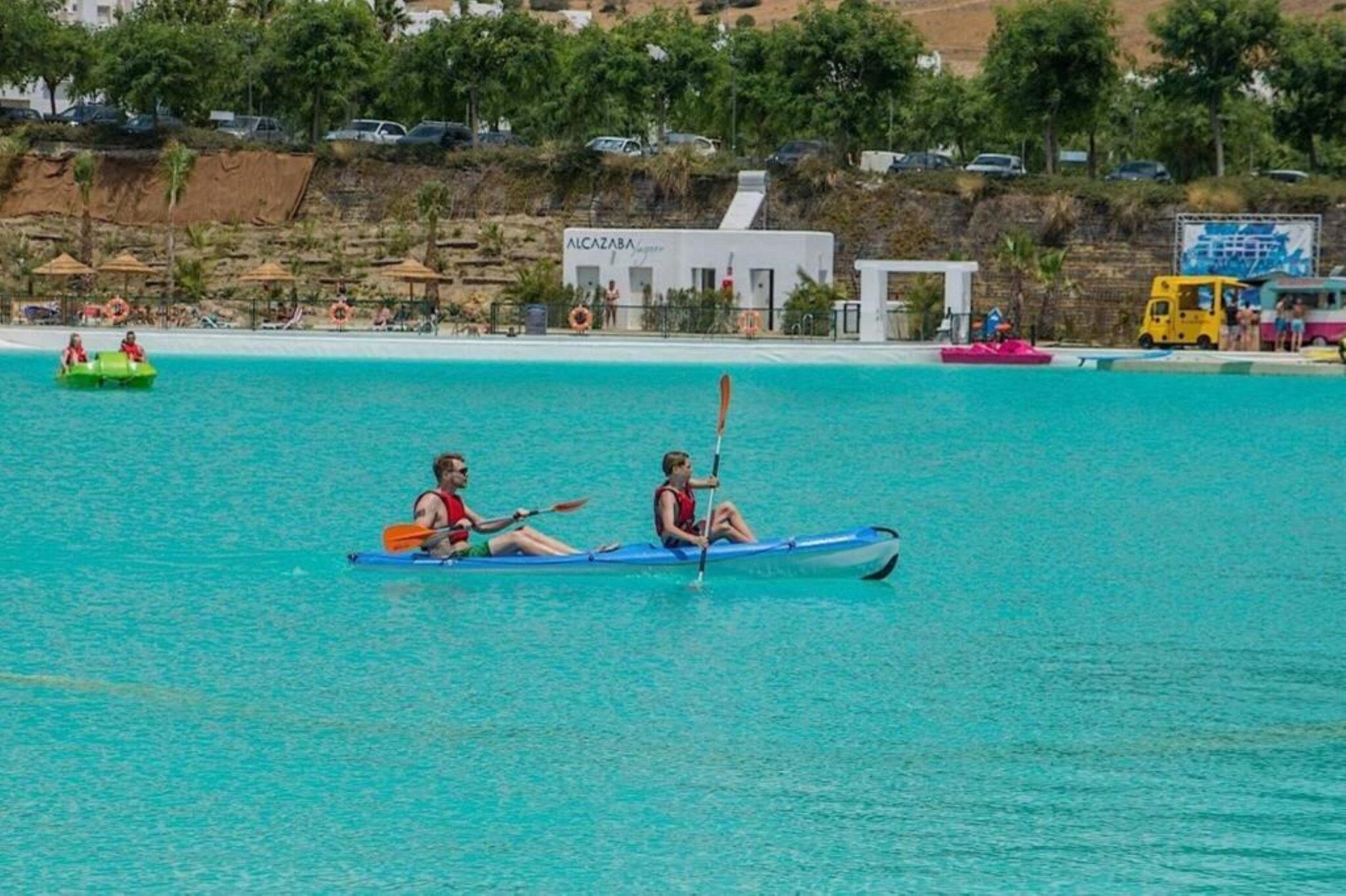 Una masa de agua tranquila con kayaks y un bote pequeño.