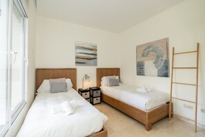 Une chambre d’hôtel avec deux lits, une tête de lit en bois, une table de chevet avec une lampe, un tableau au mur et une échelle en bois.
