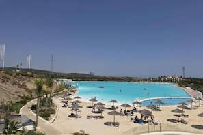 Ein Strandresort mit einem großen Schwimmbecken, Liegestühlen und Sonnenschirmen.
