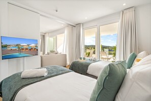 Ein Hotelzimmer mit zwei Betten, einem Fernseher und einem Balkon mit Blick auf den Pool.