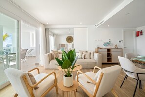 Un salon moderne comprenant un canapé, deux fauteuils, une table basse et une plante en pot.