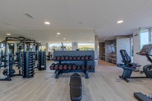 Une salle de sport équipée de matériel de musculation, de tapis de course et d’un banc.