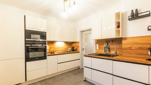 Eine moderne Küche mit weißen Schränken, einem eingebauten Backofen, einer Holz Arbeitsplatte und einem Spülbecken.