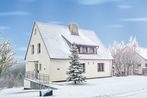 A two-story house with a snow-covered roof and a small tree in front. - Hiking & Wellness · Sauna, Hot Tub, Fireplace (Winterberg)