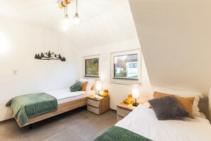 A bedroom with two beds, a nightstand, a lamp, and a wall decoration. - Hiking & Wellness · Sauna, Hot Tub, Fireplace (Winterberg)