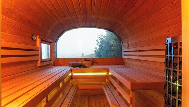 Eine Sauna mit Holzbänken und einer Sitzbank in der Mitte.