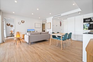 A modern living room with a sofa, a dining table with chairs, and a kitchen area with appliances. - Elegant 4-Pax Apartment in Casares (Casares)