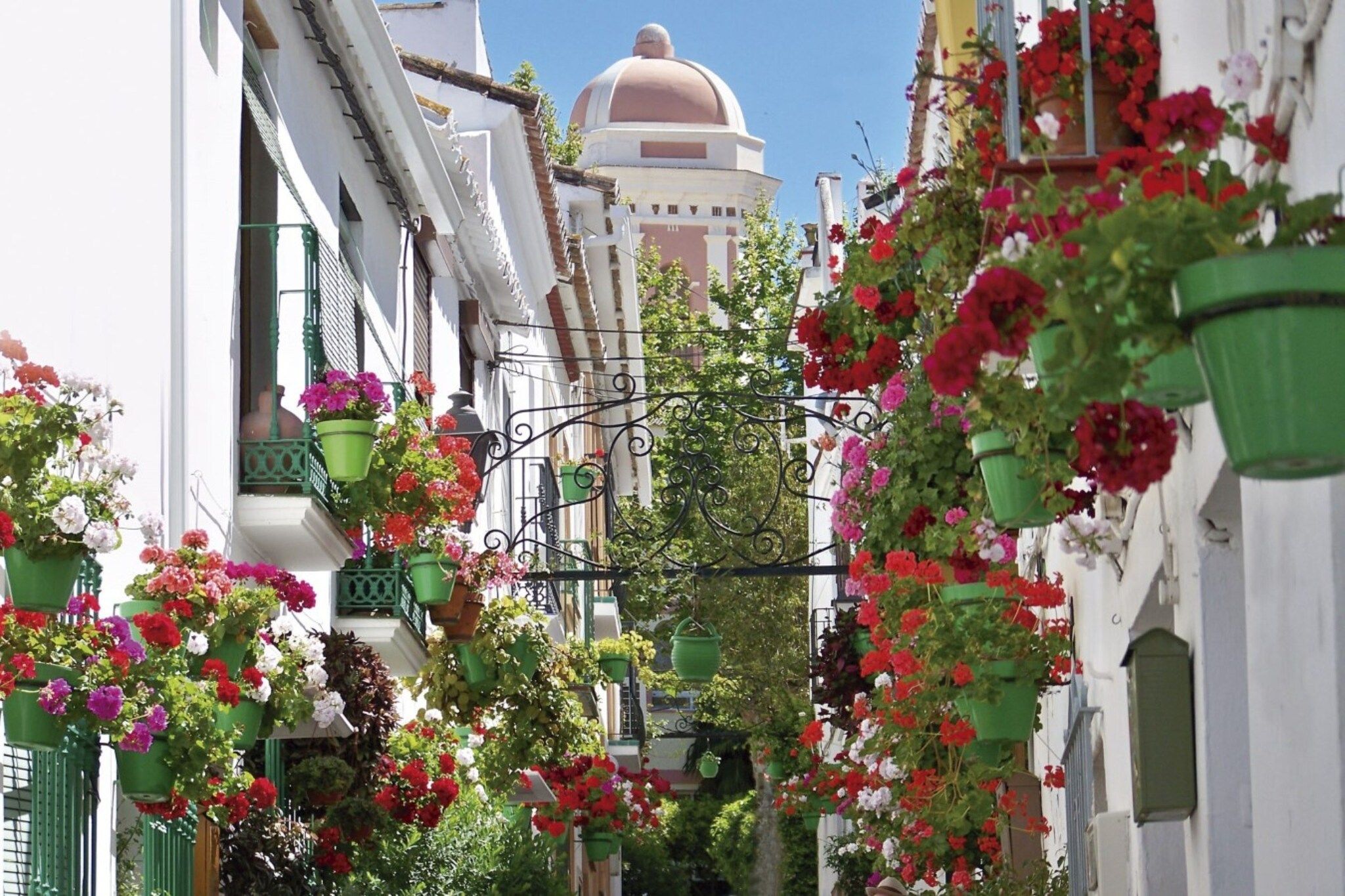 Eine schmale Straße, gesäumt von Häusern mit Balkonen und Blumenkörben.