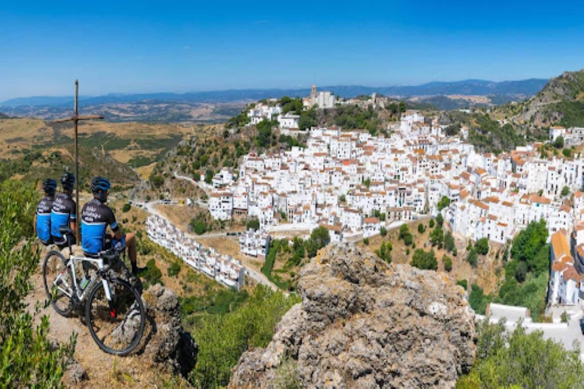 A mountainous town with white buildings, a clear sky, and a rocky foreground.