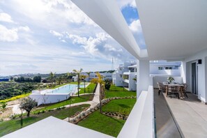 Un immeuble résidentiel moderne doté d’une piscine, d’un espace extérieur aménagé et offrant une vue sur le paysage environnant.