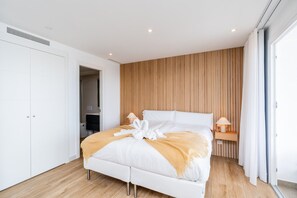A modern bedroom with a bed, bedside lamps, a wooden panel wall, and a white wardrobe. - Stylish Lagoon Apartment for 4 (Casares)