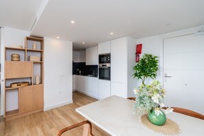 A modern kitchen with white cabinets, a dining table with chairs, and a green vase with flowers. - Stylish Lagoon Apartment for 4 (Casares)