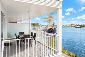 A balcony with a table and chairs, overlooking a marina with boats and a sailboat. - Villa Promenade 03, Apartment 09 (Lübeck-Travemünde)