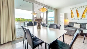 Une chambre d’hôtel moderne dotée d’un coin repas, d’un canapé et d’une grande fenêtre offrant une vue sur la ville.