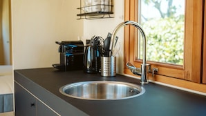 Una cocina con un lavamanos de acero inoxidable, una cafetera y un portalapices.