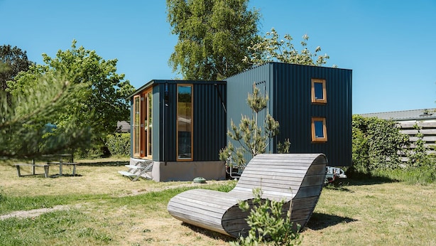 Un área de estar al aire libre moderna con una silla lounge de madera, una mesita de madera y una mesa de picnic.