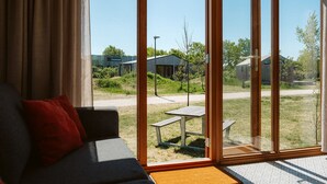 Habitación moderna con un amplio ventanal corredero que da a un espacio exterior con mesa de picnic y vegetación.