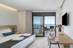 A hotel room with a bed, a desk, a chair, a TV, and a balcony with a view of the ocean. - Nelisa, A Private Sanctuary of Sun, Sea & Timeless Luxury in Crete (Vlychada)