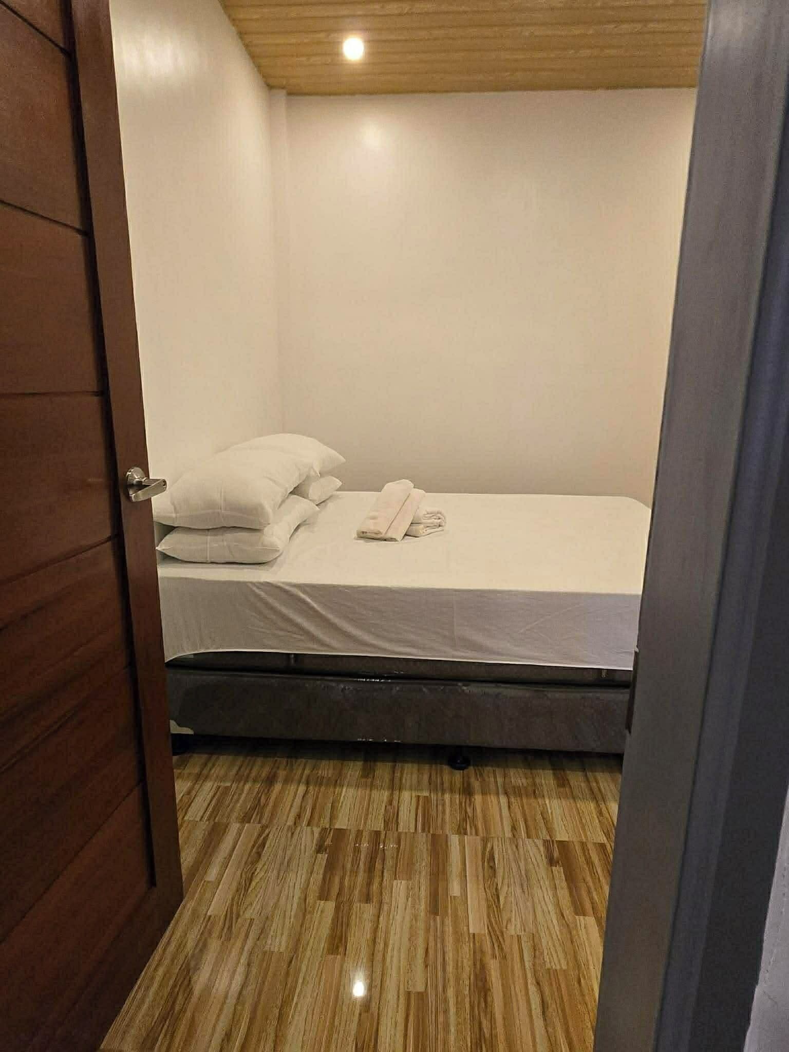 Una cama pequeña y bien hecha en una habitación con suelo y techo de madera.