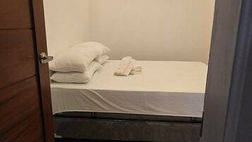 Una cama pequeña y bien hecha en una habitación con suelo y techo de madera.