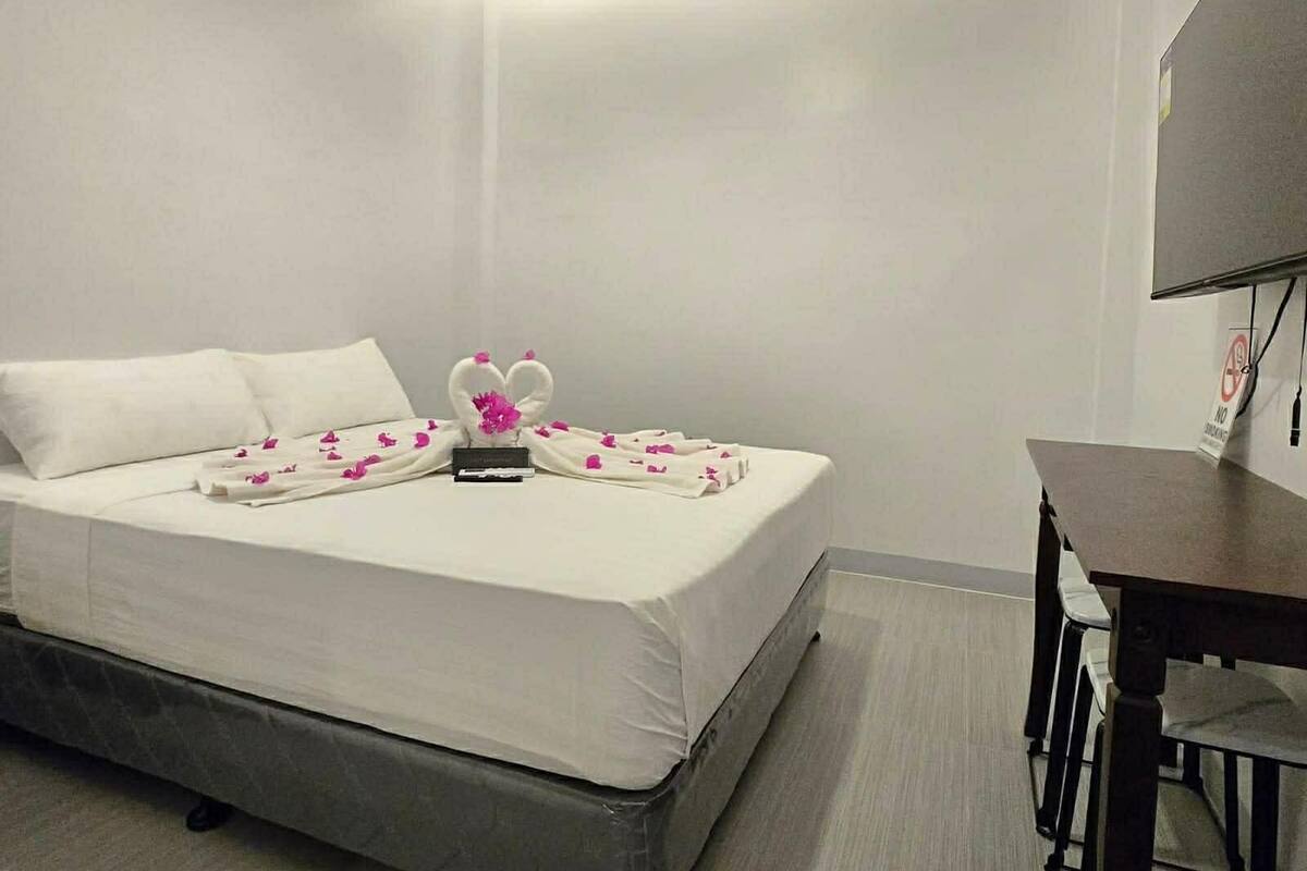 A hotel room with a bed, a desk, and a chair.