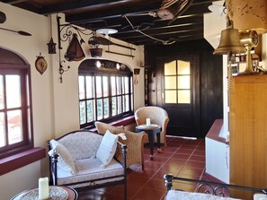 A cozy room with a sofa, a chair, a small table with a candle, and a wooden cabinet.