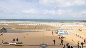 A beach with a row of beach huts, a pedestrian path, and a sign for 'strandtib'. - 3 bedroom accommodation in Nieuwpoort (Nieuwpoort)