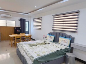 A bedroom with a bed, a desk, and two windows with blinds. - Mini House 365 Holdings Ly Tu Trong (Thoi Binh)
