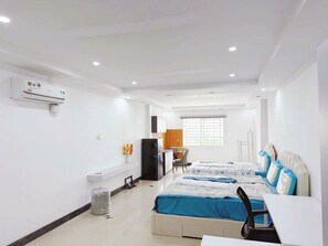 Ein Hotelzimmer mit Bett, Schreibtisch, Stuhl, Mülleimer und Klimaanlage.