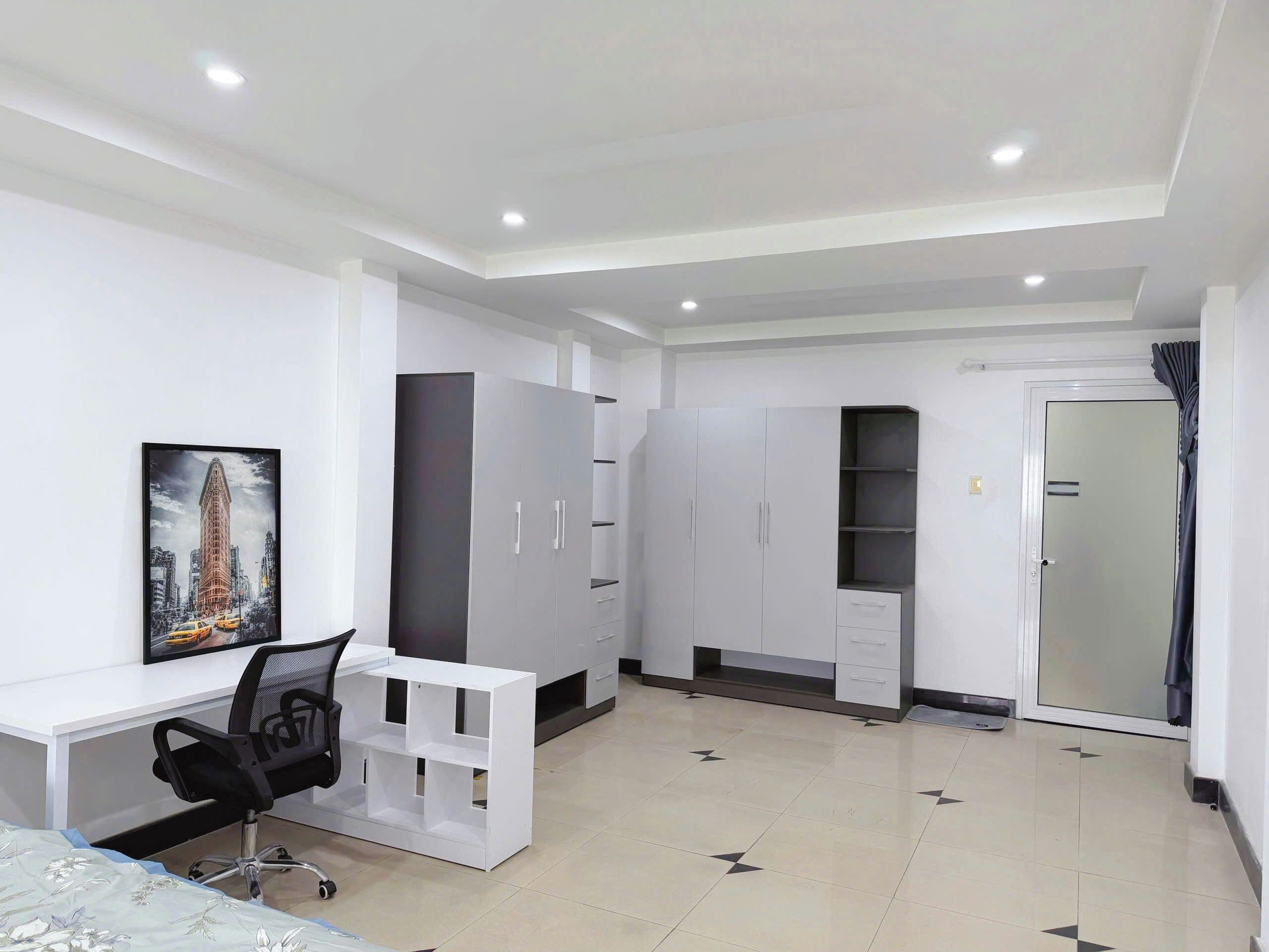 Une chambre à coucher avec un lit, un bureau, une chaise, une armoire et une porte.