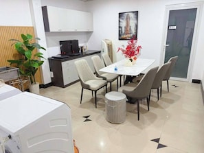 A modern kitchen with white cabinets, a black countertop, and a dining area with a table and chairs.